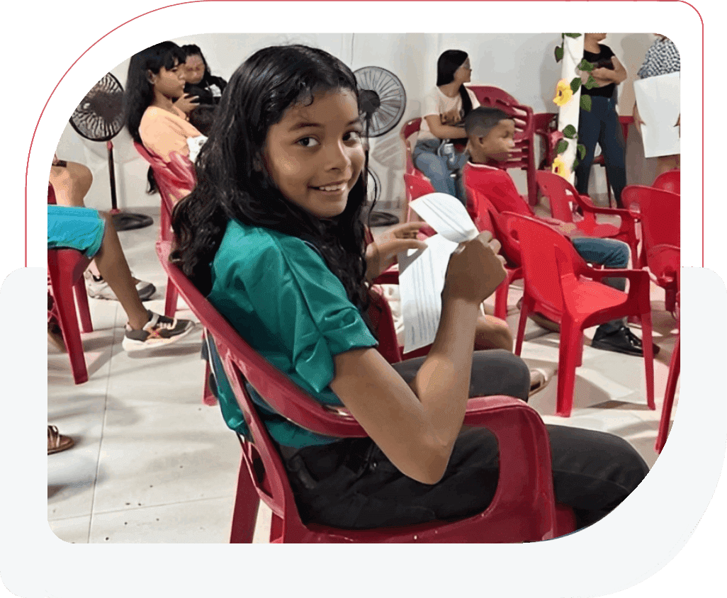 Girl sitting on a red chair enjoying an ice cream cone.