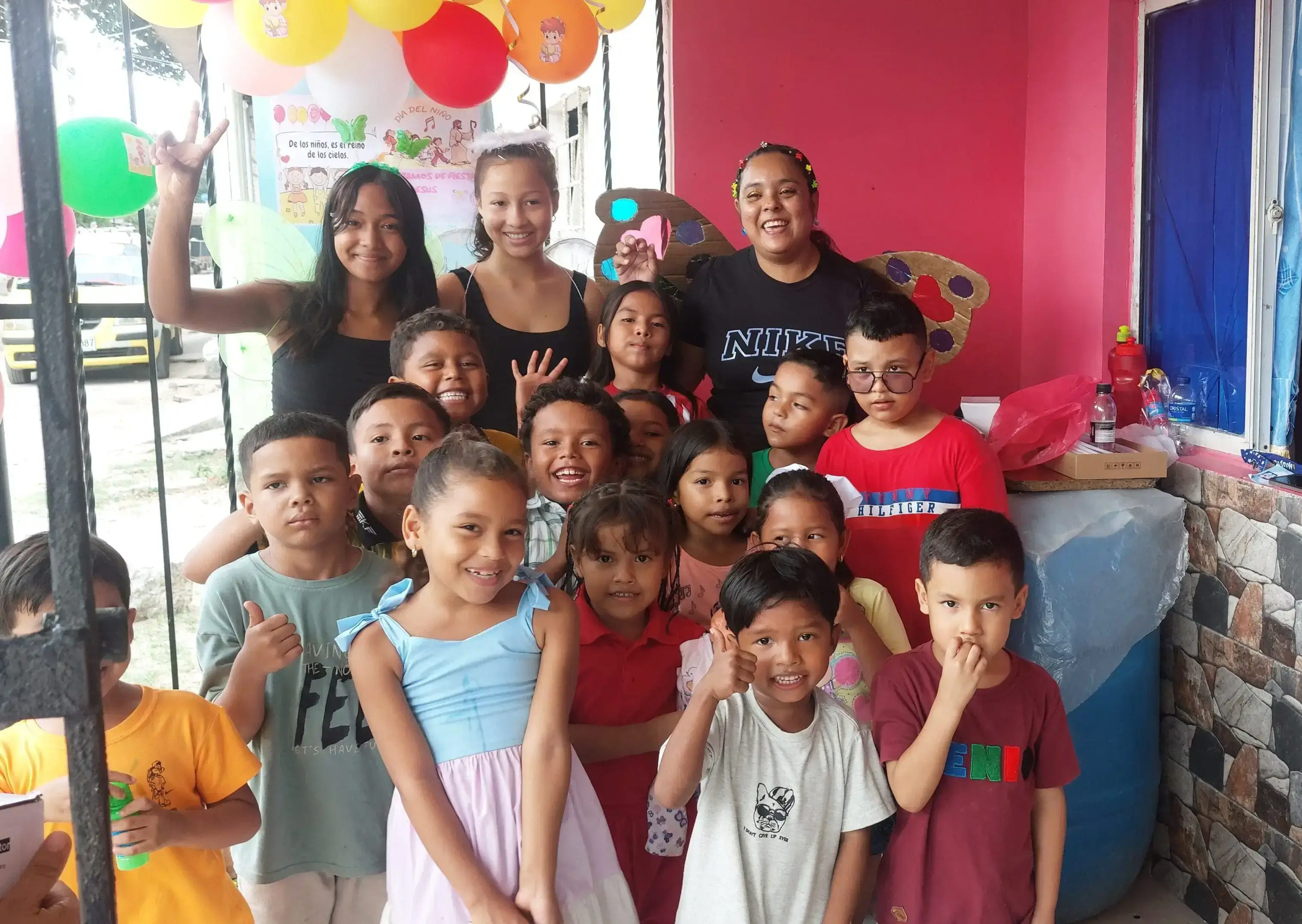 A group of children and adults smiling at a colorful party.